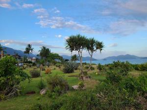 a park with palm trees and a view of the ocean at Linda casa a 200m da Praia do Capricórnio in Massaguassu