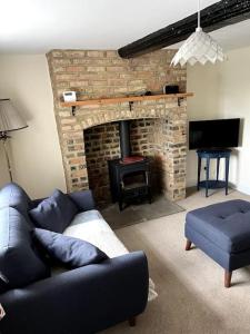 ein Wohnzimmer mit einer Couch und einem gemauerten Kamin in der Unterkunft Fern Cottage in Brinklow