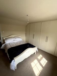 ein Schlafzimmer mit einem weißen Bett und einer schwarzen Decke in der Unterkunft Fern Cottage in Brinklow + 12 Fotos