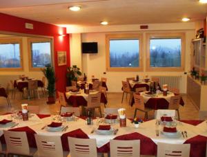 Residence Hotel Matilde في Carpineti: مطعم بطاولات بيضاء وكراسي ونوافذ