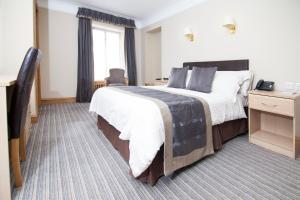 een hotelkamer met een groot bed en een televisie bij Burnett Arms Hotel in Banchory