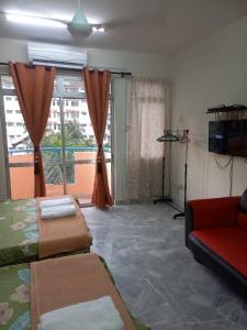 a living room with a red couch and a large window at PD BATU 9 Cocobay Resort Condominium in Kampong Tanah Merah +3 photos