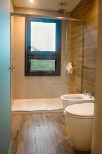a bathroom with a shower and a toilet and a window at Iguazu Jungle Lodge in Puerto Iguazú