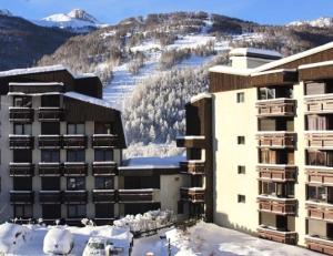 un edificio en la nieve con montañas en el fondo en Résidence Les Mélèzes - 2 Pièces 4 Personnes MAE-8740, en Champcella