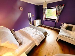 a bedroom with purple walls and a bed and a window at Gorgeous Family 3 Bedroom Home in Newbury