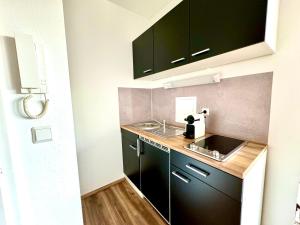 a small kitchen with black cabinets and a sink at Chices Service Apartment nahe Homburger Uni Klinik und Technologiepark mit Loggia und kostenlosem Parkplatz in Homburg +3 photos