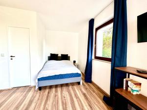 a bedroom with a bed with blue curtains and a window at Chices Service Apartment nahe Homburger Uni Klinik und Technologiepark mit Loggia und kostenlosem Parkplatz in Homburg