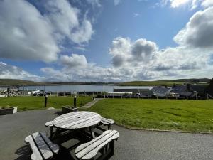 a picnic table and two benches in front of a field at St Magnus Bay Hotel in Hillswick