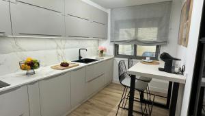 a white kitchen with a sink and a counter with chairs at Piso Porta do Sol in Ribeira