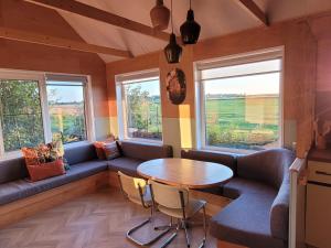 a room with a couch and a table and two windows at Dijksterhuisje in Pieterburen
