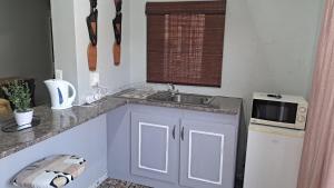 una cocina con fregadero y microondas en At Home Guest House, en Postmasburg