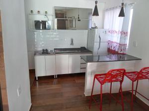 a kitchen with white cabinets and red stools at kitnet com garagem exclusiva in Venda Nova