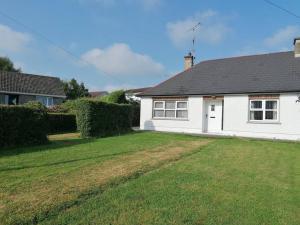 a white house with a black roof and a yard at Rossole Cottage in Enniskillen