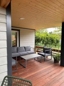 eine Veranda mit einem Sofa und Stühlen auf einer Terrasse in der Unterkunft Ô Ptit Bouleau in Buhl-Lorraine