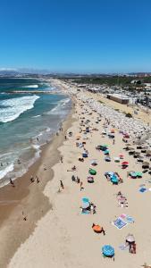 a group of people on a beach with umbrellas at Big house with pool - 5 min walk to beach in Costa da Caparica