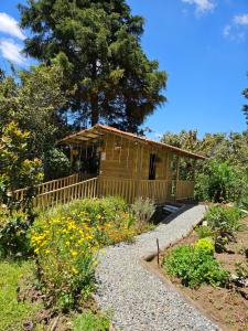 a small wooden cabin with a garden with flowers at Casa De Campo "Las Chispas" in Medellín
