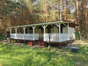 a white house with a porch in the woods at Leśna Holenderka in Nowa Brzeźnica