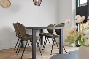 a dining room table with chairs and a clock on the wall at Vakantiehuis Nieuwdorp in Nieuwdorp
