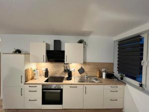 a kitchen with white cabinets and a sink and a window at FeWo Foorden Wohnglück 2 in Hesel +7 photos