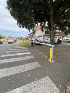 a street with a tree and cars parked on the street at Studio rénové proche de la plage in Tarnos
