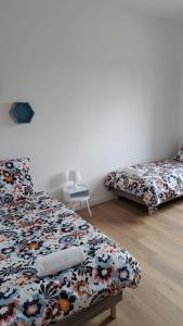 a bedroom with two beds with a floral bedspread at Appartement Miami près de Douai in Flers-en-Escribeus