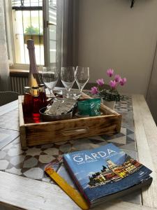 a wooden tray with wine glasses and a book on a table at Intellihost - Casa Giulietta Lonato del Garda in Lonato