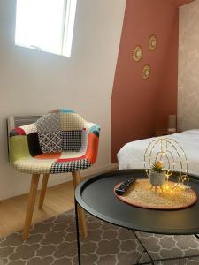 a living room with a table and a chair at Savanah - Olympe Suites & Spa Roubaix - Lille in Roubaix +9 photos