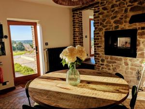 a wooden table with a vase with flowers on it at La Petite Maison dans la Prairie in Pepinster