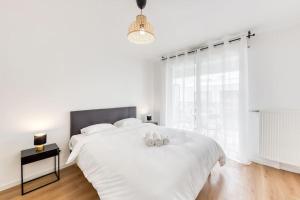 ein weißes Schlafzimmer mit einem großen weißen Bett mit zwei Kissen in der Unterkunft L'Elégant de Paris - Villepinte - Paris in Villepinte