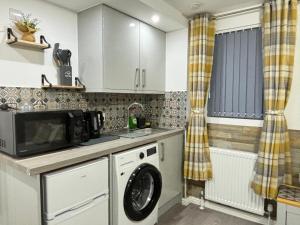 a kitchen with a washing machine and a microwave at Gatwick Lodge in Horley +3 photos