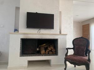 a living room with a fireplace with a television above it at Villa Jackbeach front mer in Dar Bouazza