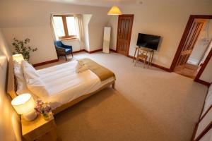 a hotel room with a bed and a television at Woodlands House with Hot Tub in Ballachulish