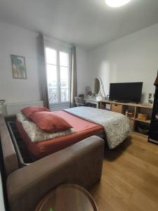 a bedroom with a bed and a desk with a television at Chez Caramel à Vincennes in Vincennes