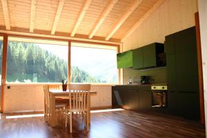 a kitchen with a table and chairs and a large window at Rumwaldhof - Wohnung Enzian in Solda