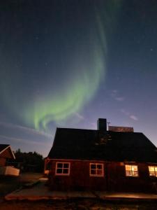 a house with the aurora in the sky behind it at Bungalåven Lodge AS in Børselv