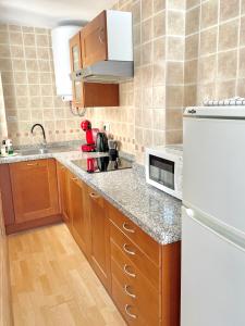 a kitchen with wooden cabinets and a white refrigerator at Apartment with terrace in Ardales