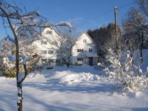 a snow covered yard with a white house at Ferienhaus am Lech in Kaufering