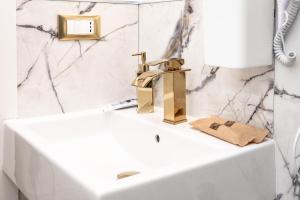 a bathroom with a sink and a gold faucet at Maison 31 - Junior Suite in Santa Marinella