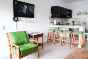 a living room with green chairs and a kitchen at Remodeled Cozy Central 3 blocks from the Malecon in Mazatlán