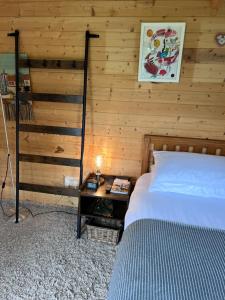a bedroom with a bed and a wooden wall at The Cabin in Bradford on Avon