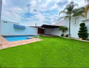 a house with a green lawn and a swimming pool at Casa Jarana in Oaxtepec