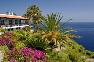 a building with plants and flowers in front of the ocean at Hotel Jardín Tecina in Playa de Santiago