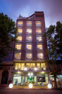 a tall brick building with windows and a balcony at Hotel Royal in Colonia del Sacramento