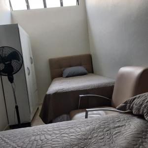 a bedroom with a bed and a chair and a fan at Apartamento 2 quartos Asa Norte com cozinha excelente localização in Brasilia