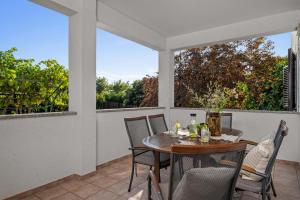 a patio with a wooden table and chairs and two windows at Holiday Home Katharina in Labin