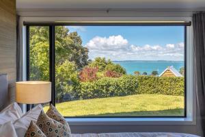 a bedroom with a large window with a view of the water at Pacific Escape, Oneroa - Be My Guest Waiheke in Oneroa +54 photos