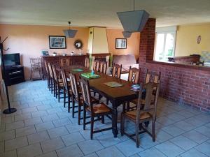 a dining room with a long wooden table and chairs at Gîtes à la ferme in Friville-Escarbotin