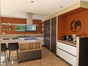 a kitchen with orange walls and a counter and chairs at Cocon familial proche des plages 10 personnes in Quimper