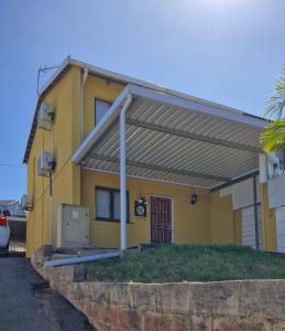 a yellow house with awning in front of it at Shisa Cottage in Durban