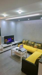 a living room with a yellow couch and a tv at Appartement meublé harhora in El Harhoura